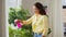 Asian woman spraying houseplant with water at home