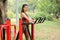 Asian woman stand and exercise with equipment in park or garden also look at camera and smile