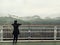 Asian woman standing alone on balcony looking at white foggy and mountains background