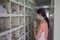 Asian woman standing at Chinese style columbarium paying praying in front of cinerary urns of ancestor