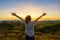 Asian woman standing and hand up in tropical forest and looking far away at sunrise time