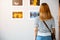 Asian woman standing she looking art gallery in front of colorful framed paintings pictures