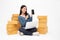 Asian woman startup small business freelance holding parcel box, mobile phone and computer laptop and sitting on floor