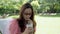 Asian woman sucking iced green tea from straw in garden.