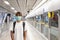 Asian woman with surgical face mask feel tired standing waiting for subway, skytrain, carrying backpack, traveling