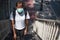 Asian woman with surgical face mask, standing on overpass bridge stairs