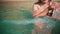 an Asian woman is swimming on the beach with blue sea water when she sits on the beach sand