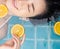 Asian woman is swimming with a slice of orange floating above the water in a blue pool