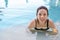 Asian woman in swimsuit smiling in swimming pool, active summer vacation concept