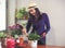 Asian woman  taking care of plant  at wooden table indoor ,using garden spoon and smiling happily..Gadening concept