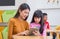 Asian woman teacher teach girl student with tablet computer in classroom at kindergarten preschool,Online education concept