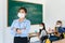 Asian woman teacher wearing masks to prevent the outbreak of Covid 19 in classroom with student while back to school reopen their