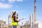 Asian woman technician Industrial engineer using walkie-talkie and holding bluprint working in oil refinery for building site