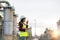 Asian woman technician Industrial engineer using walkie-talkie and holding bluprint working in oil refinery for building site