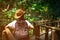 Asian woman tourist with hat and backpack standing and start walking on nature trail bridge in tropical forest.