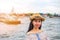 Asian woman tourist wear hat standing smiling with the background is a view of chao phraya river and pagoda arun temple landmark