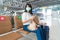 Asian woman tourist wearing mask using mobile phone searching airline flight status and sitting social distancing chair in airport