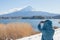 Asian woman traveler taking photograph beautiful landscape view of fuji mountain covered with white snow in winter seasonal.