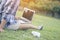 Asian woman typing the keyboard of laptop on the green grass in the park