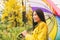 Asian woman under colorful umbrella on rainy day of Autumn, rain fall fashion lifestyle girl walking in forest with