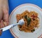 Asian woman using a fork to scoop Spicy spaghetti pork. Drunken Spaghetti Thai call Popular in street food