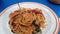 Asian woman using a fork to scoop Spicy spaghetti pork. Drunken Spaghetti Thai call Popular in street food