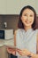 Asian woman using tablet to find recipe making smoothie with fruit and vegetable in kitchen