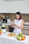 Asian woman using tablet to find recipe making smoothie with fruit and vegetable in kitchen