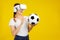 Asian woman in VR headset and holding a soccer ball isolated yellow background, Sport and Metaverse