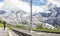 Asian woman waiting for Swiss railways train from Kleine Scheidegg at Wengernalp station with view of beautiful majestic swiss alp