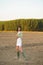 Asian woman, walking in the countryside, wearing a white dress and green wellies.