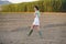 Asian woman, walking in the countryside, wearing a white dress and green wellies.