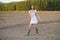 Asian woman, walking in the countryside, wearing a white dress and green wellies.