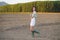 Asian woman, walking in the countryside, wearing a white dress and green wellies.