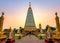 Asian woman walking in golden stupa Sri Maha Pho Chedi with colorful evening sky at Wat Phra That Nong Bua, Ubon Ratchathani