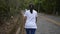 Asian woman walking through the hill on the road. View from rear side of female people aiming to the mountain.