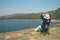 Asian woman wear hat and sitting relax on portable chair nearly lake at National Park.