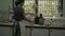 Asian woman wearing apron preparing and cleaning utensils on the dish cabinet in the kitchen next to the window in the morning.