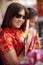 Asian woman wearing chinese tradition suit and holding bamboo fan with toothy smiling face in bangkok china town