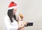 Asian woman wearing  red Santa Christmas hat  holding  and taking selfie photo with  her Chihuahua dog wearing reindeer horn hat