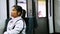 Asian woman wearing white sportive shirt sits in moving train and looks around.