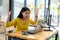 Asian woman wears a yellow shirt, look at the laptop screen and shows a serious manner