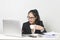 Asian woman working with laptop at white working table, diligent professional working woman drinking coffee while working on lapto