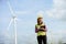 Asian woman in yellow helmet working with digital tablet at renewable energy farm. Female inspector controlling functioning of