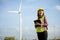 Asian woman in yellow helmet working with digital tablet at renewable energy farm. Female inspector controlling functioning of