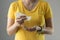 Asian Woman in yellow shirt standing over grey background is pouring hand sanitizer portable gel on her palms and hands for