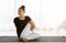 Asian women doing yoga seated twisting exercise at home, sitting in Lord of the Half Fishes Pose or Ardha Matsyendrasana, in white