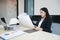 Asian women engineering holding blueprints and have hard hat on table  for working at office