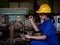 Asian women in mechanic uniforms are using power tools to drill metal bars in the factory