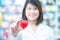 Asian women medical doctor holding a red heart ball with blurred background. Concept of health care